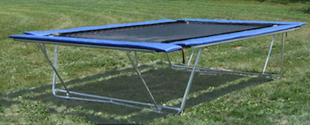 A Backyard Pro® trampoline is shown outside on a lawn in its above-ground mode. It can also convert to a ground-level installation.